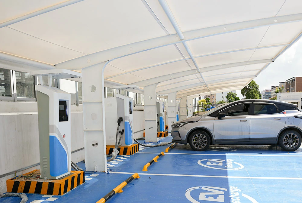 A modern commercial EV supercharger station with multiple vehicles charging at high-power DC fast charging ports in a retail parking lot.
