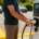 Man holding an electric vehicle charger in a parking lot, preparing to charge his car, illustrating EV charging business opportunities and future commercial charging potential