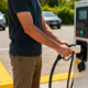 Man holding an electric vehicle charger in a parking lot, preparing to charge his car, illustrating EV charging business opportunities and future commercial charging potential