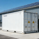 An industrial solar battery storage solution featuring a 20ft containerized BESS installed next to a factory warehouse.