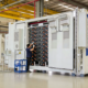 engineers inspecting 5MWh liquid-cooled BESS container in factory, battery energy storage system testing and quality assurance before deployment