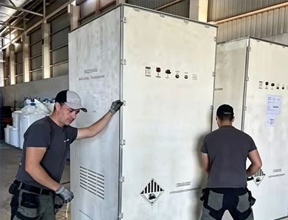 workers handling and positioning BESS container inside warehouse before transportation