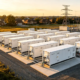 A large-scale battery storage plant featuring multiple BESS containers connected to the power grid for utility energy storage.