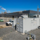 A high-capacity 1MW battery storage system for manufacturing plants installed on a concrete foundation next to a factory substation.