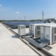 An integrated 20ft BESS container installed on a site foundation pad alongside solar PV panels for optimal commercial energy storage.