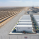 Aerial view of a large scale solar farm with single-axis tracking panels and high-voltage grid substation