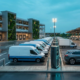 Commercial EV fleet charging solutions layout showing delivery vans charging overnight with Level 2 AC units alongside a dual-port DC fast charger at an industrial depot.