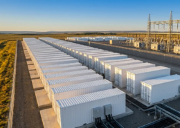 Utility-scale battery storage system containers connected to a high-voltage grid substation.