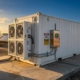 Containerized hybrid battery energy storage system deployed outdoors alongside solar panels for commercial power support
